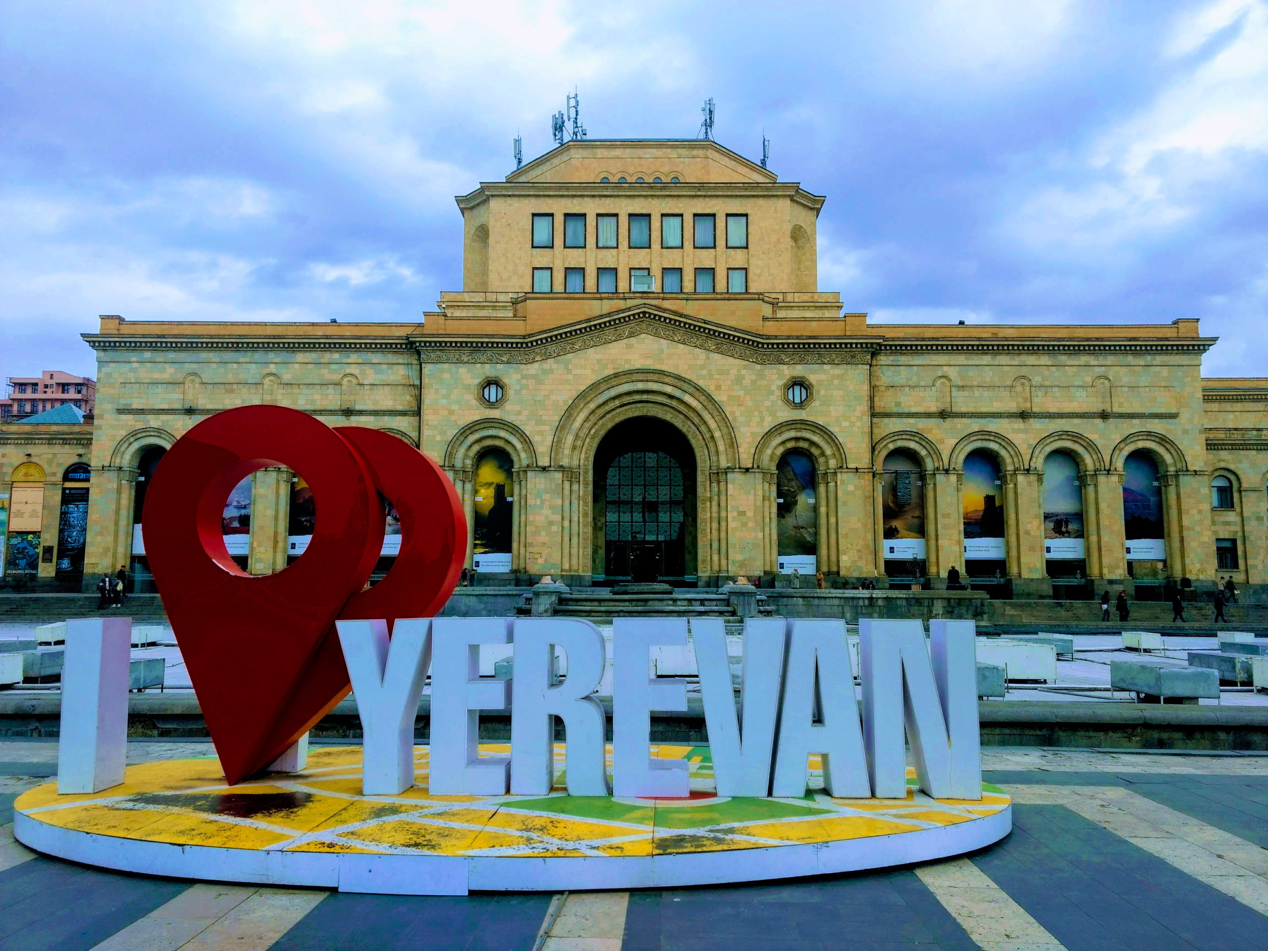 Cartel sobre la capital Ereván en la Plaza de la República, detrás el Museo de historia de Armenia